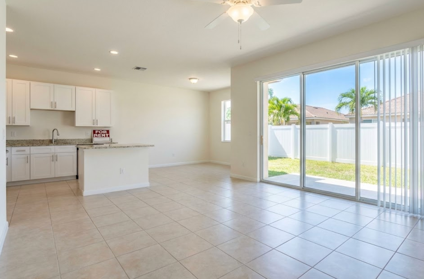 Empty renovated rental unit with a for rent sign on the kitchen counter and sunlight coming through sliders