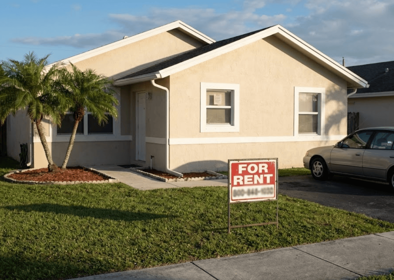 Corner-lot rental home with a for rent sign and a parked car